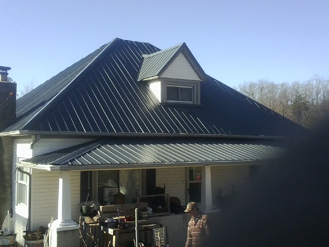 Dark blue standing seam metal roof with a dormer above a front porch in North Bend