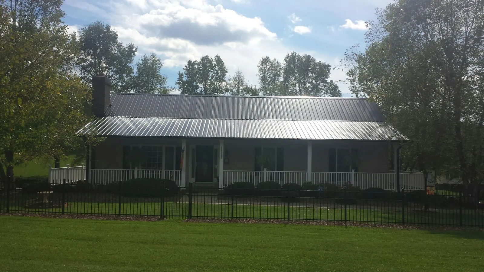Gray metal roof on a brick ranch with a full width front porch — Gutter Guard Installation work by our crew in North Bend