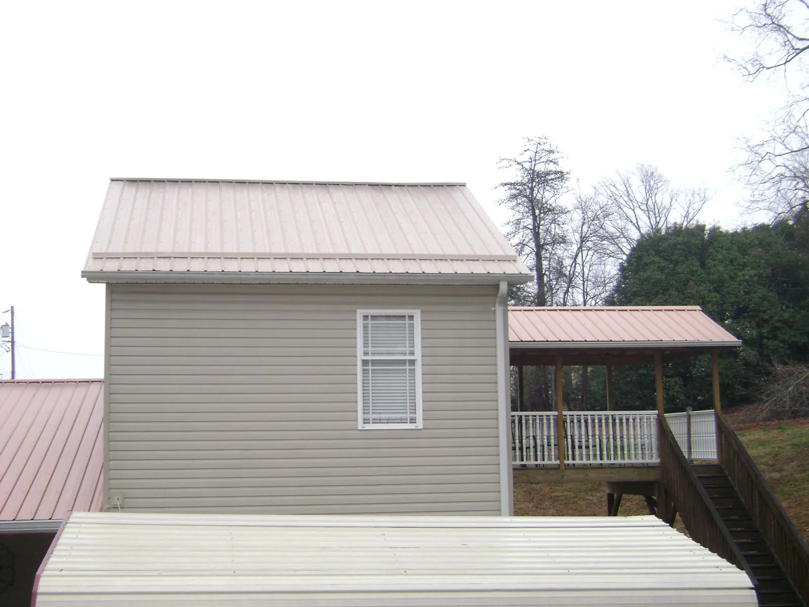 Tan metal roofs on a two story addition and attached porch, from a Roof Replacement job in North Bend
